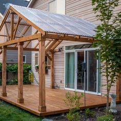 a wooden deck with a metal roof next to a house