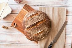 a loaf of bread sitting on top of a wooden cutting board next to a knife