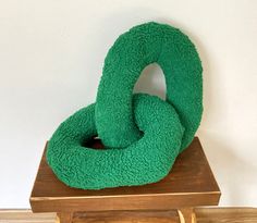 a green stuffed animal sitting on top of a wooden table next to a white wall