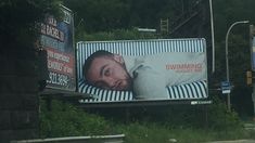 a billboard with a man's face on it next to a street sign that says swimming