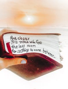 a hand holding an open book that has writing on it with the sun in the background