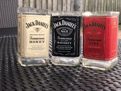 three bottles of jack daniels are sitting on a patio table with wicker chairs behind them