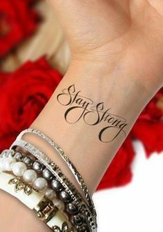 a woman's wrist with a tattoo saying stay strong on it and pearls around the wrist