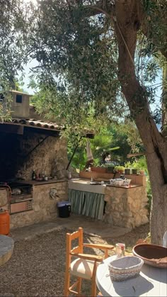 an outdoor kitchen is set up next to a tree and table with chairs around it