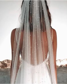 the back of a woman wearing a wedding veil with pearls on it's side