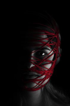 a woman's face is covered in red string