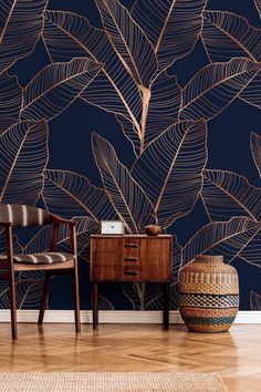 a chair and table in front of a blue wall with gold leaves on it