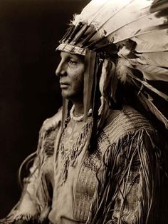 an old black and white photo of a native american woman with feathers on her head