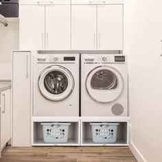 a washer and dryer in a white laundry room with cabinets on the wall