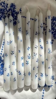 blue and white candles sitting on top of a cloth covered table next to each other