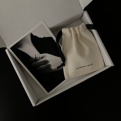 an open box containing a ring and a black and white photo with a bow on it