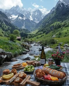 a picnic table with bread, fruit and wine in front of the mountain stream that runs through it