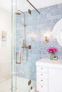 a bathroom with blue and white tiles on the walls, shower stall and sink area