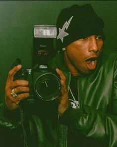 a man taking a selfie in front of a mirror with his camera and hat on