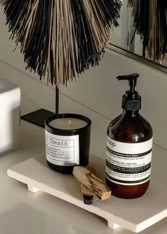 a bottle of lotion sitting next to a candle on a shelf near a mirror