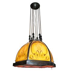 a hanging light with an ornate design on it's glass dome and metal rods