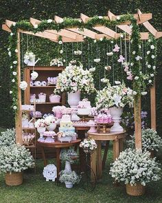 a table topped with lots of flowers next to a shelf filled with cakes and cupcakes