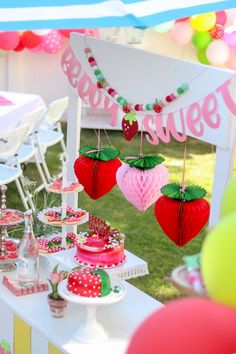 a table topped with lots of cakes and desserts covered in pink, green and red decorations