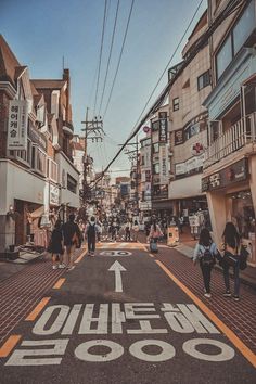 people are walking down the street in front of shops and buildings with an arrow painted on the road