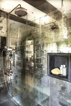 a bathroom with a glass shower stall and tiled walls, along with an old fashioned faucet