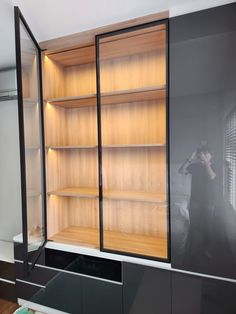 a man is taking a photo in front of a bookcase with shelves and drawers