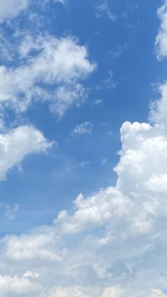 an airplane is flying high in the blue sky with white clouds and green grass below