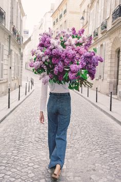 a woman walking down the street carrying a bouquet of flowers