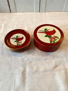 two red and white dishes sitting on top of a tablecloth covered table next to each other