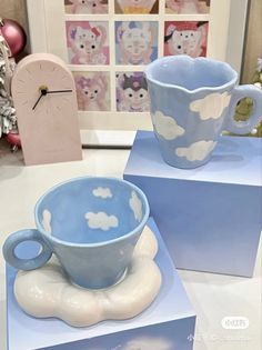 two blue and white cups sitting on top of each other in front of a clock