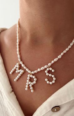 a woman wearing a white necklace with pearls on the front and back of her neck