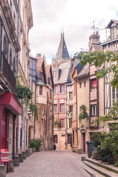 an alley way with buildings and trees on both sides, surrounded by cobblestone streets