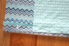 two pieces of fabric sitting on top of a wooden floor next to each other, one blue and the other white