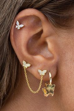 a close up of a person wearing gold ear piercings with butterflies on the side