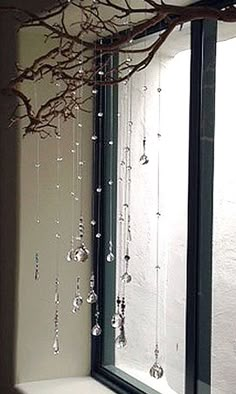 a bathroom with a tree branch hanging over the bathtub, and glass beads on the shower curtain