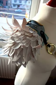 a white mannequin wearing a leather bracelet with feathers on it's wrist