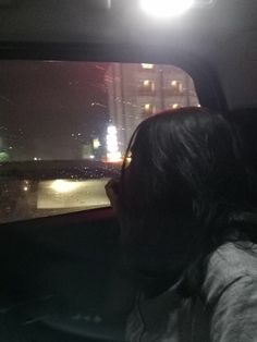 a woman is sitting in the back seat of a car at night with her headlight on