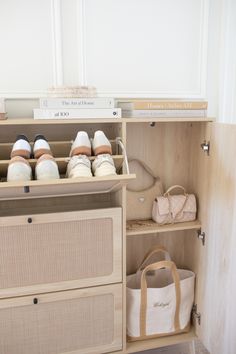 an open cabinet with several pairs of shoes and bags on top of the shelf next to it