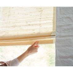 a woman's hand is reaching out from behind the blinds