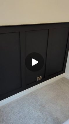 an empty room with a black cabinet and white carpet