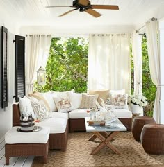 a living room filled with lots of furniture under a covered patio area next to trees