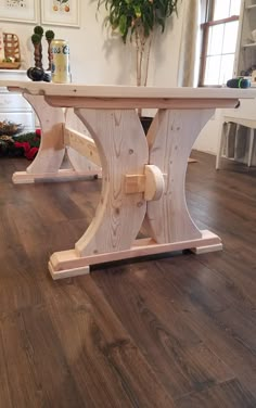 a wooden table sitting on top of a hard wood floor next to a potted plant