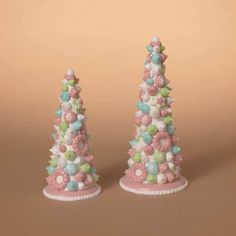 two small christmas trees with candy decorations on them, one is pink and the other is white