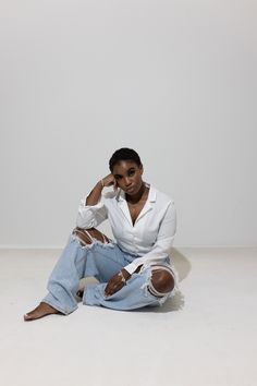 a woman sitting on the floor with her hands in her pockets