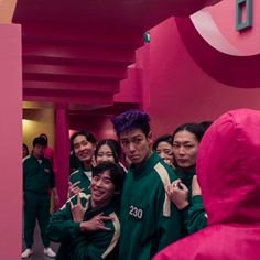 a group of young people standing next to each other in front of a pink wall