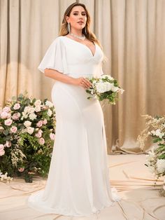 a woman standing in front of flowers wearing a white dress