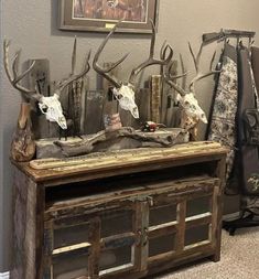 an old wooden cabinet with deer heads and antlers on the top, sitting in front of a wall