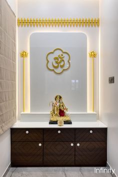 an idol sitting on top of a white counter next to a wall with gold decorations