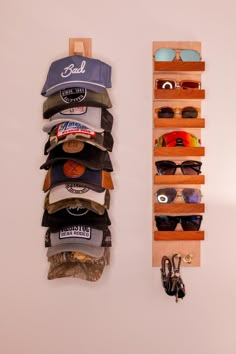 two wooden shelves with hats and sunglasses hanging on the wall next to eachother