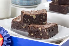 three pieces of brownie sitting on top of a white plate next to a blue ribbon