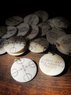 several white buttons with writing on them sitting on a wooden table next to each other